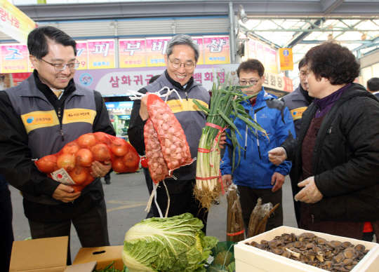 진웅섭 금감원장(왼쪽 첫번째)과 윤종규 KB국민은행장(두번째)이 4일 서울 양천구 신영시장에서 저소득 가정에 전달한 야채를 보고 있다.KB국민은행 제공